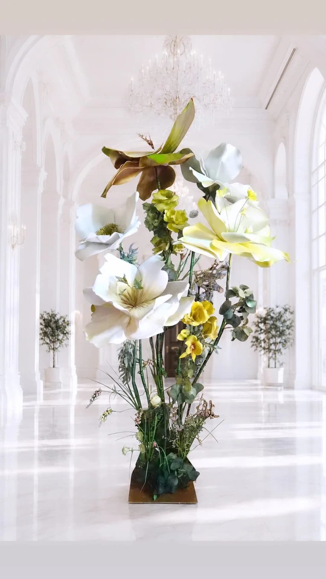 Composizione di grandi fiori bianchi e gialli su struttura, in una galleria classica