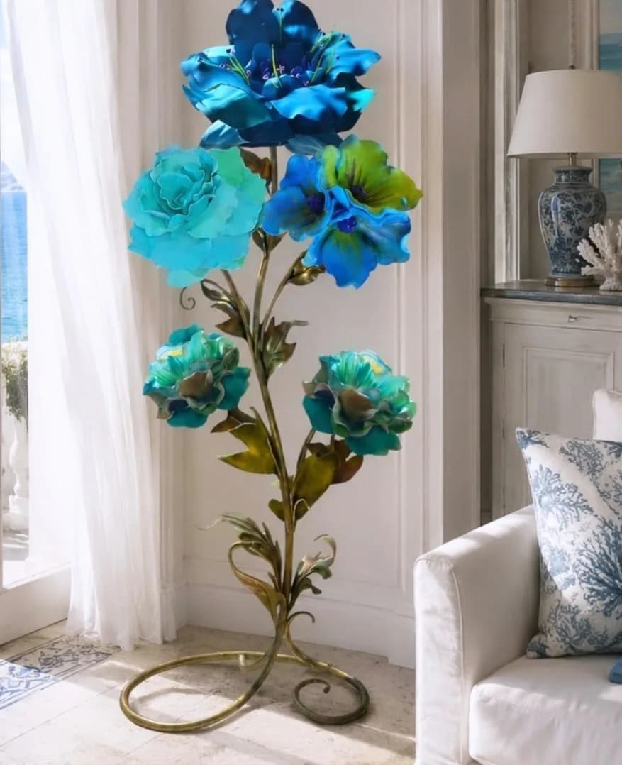 Composizione di fiori turchese e blu su struttura dorata a spirale, con vista mare