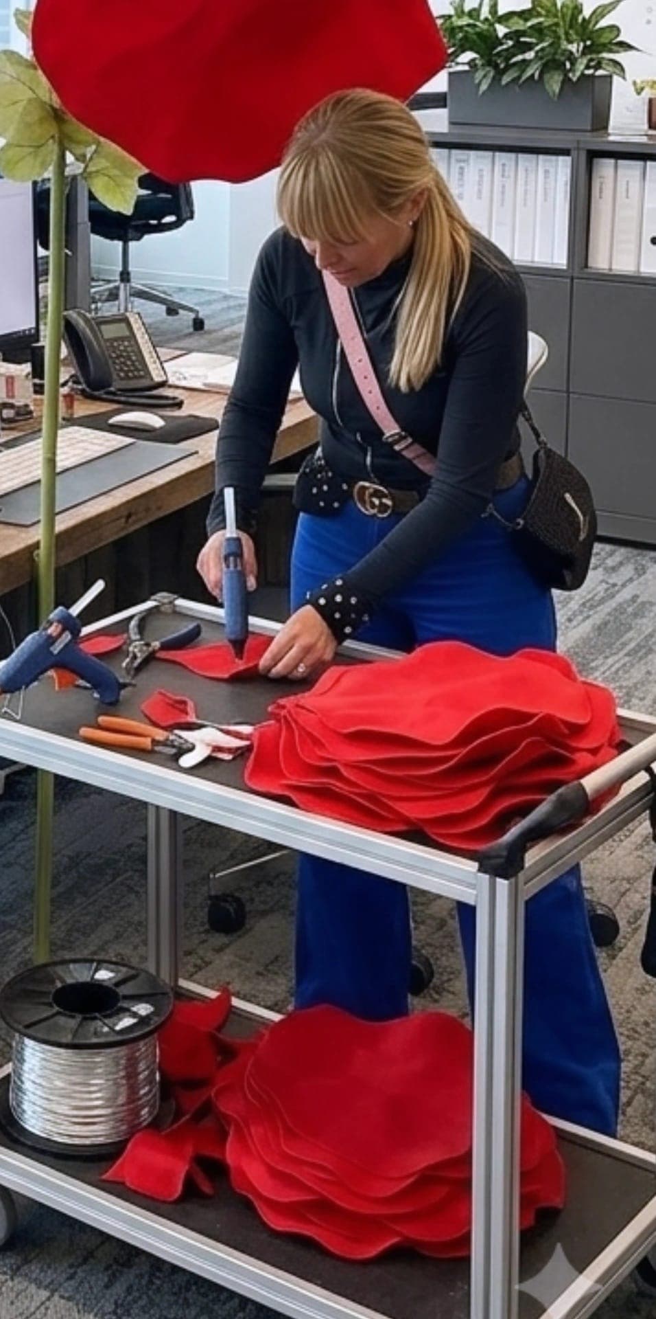 Francesca incolla i petali rossi di un papavero gigante su un carrello da lavoro