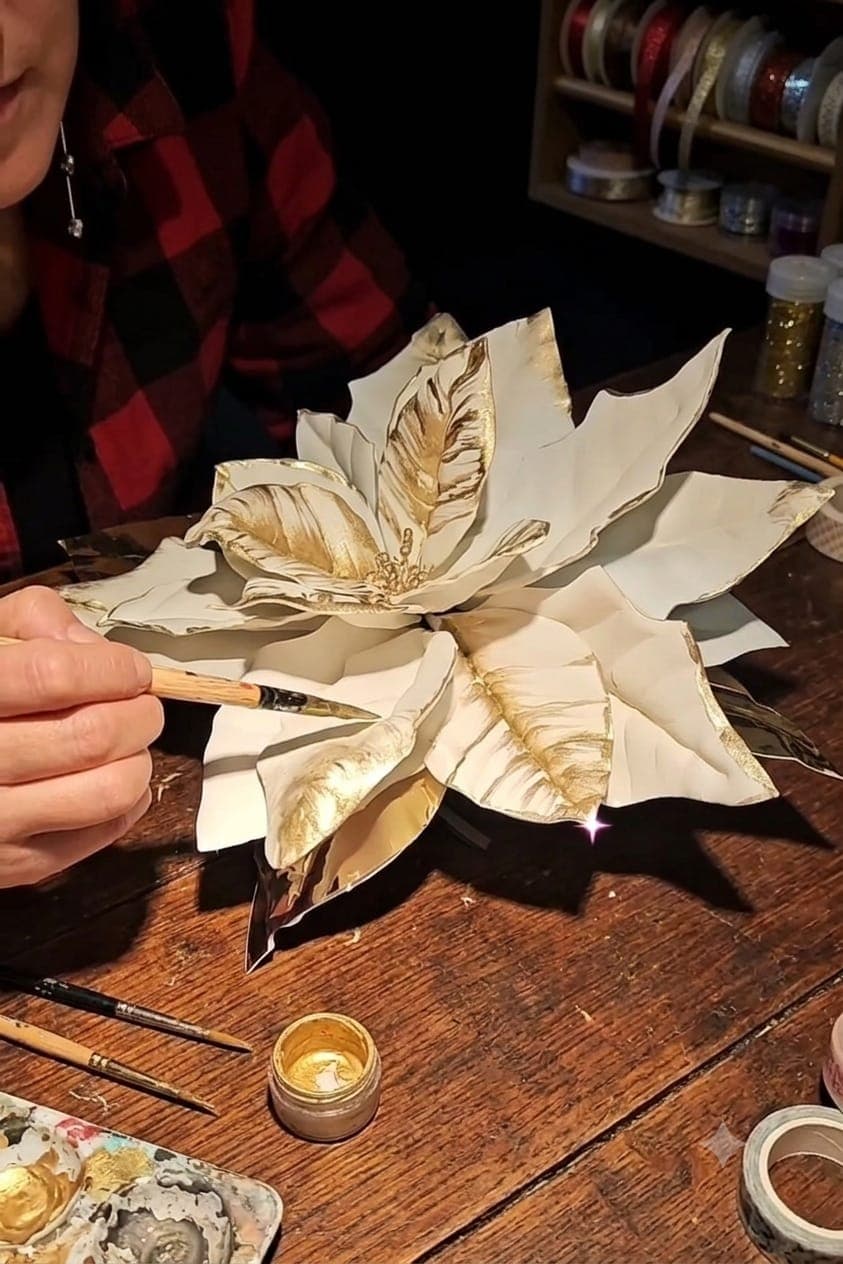 Le mani di Francesca dipingono d'oro i petali di una stella di Natale artistica